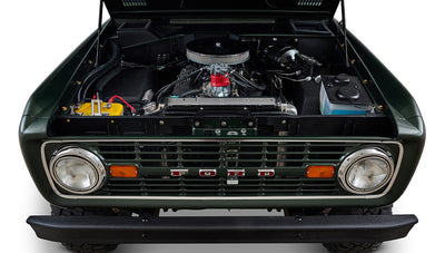 Classic Ford Bronco front view with open hood showing engine bay and front grille in dark forest green