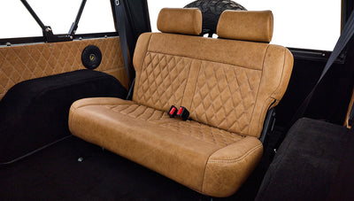 Rear tan diamond-stitched bench seat with seatbelts inside Classic Ford Bronco.