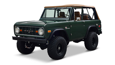 Classic Ford Bronco in dark forest green with tan soft top and lifted suspension on white studio background