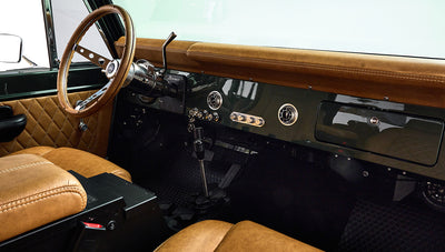 Steering wheel and dashboard of Classic Ford Bronco featuring tan upholstery and vintage controls