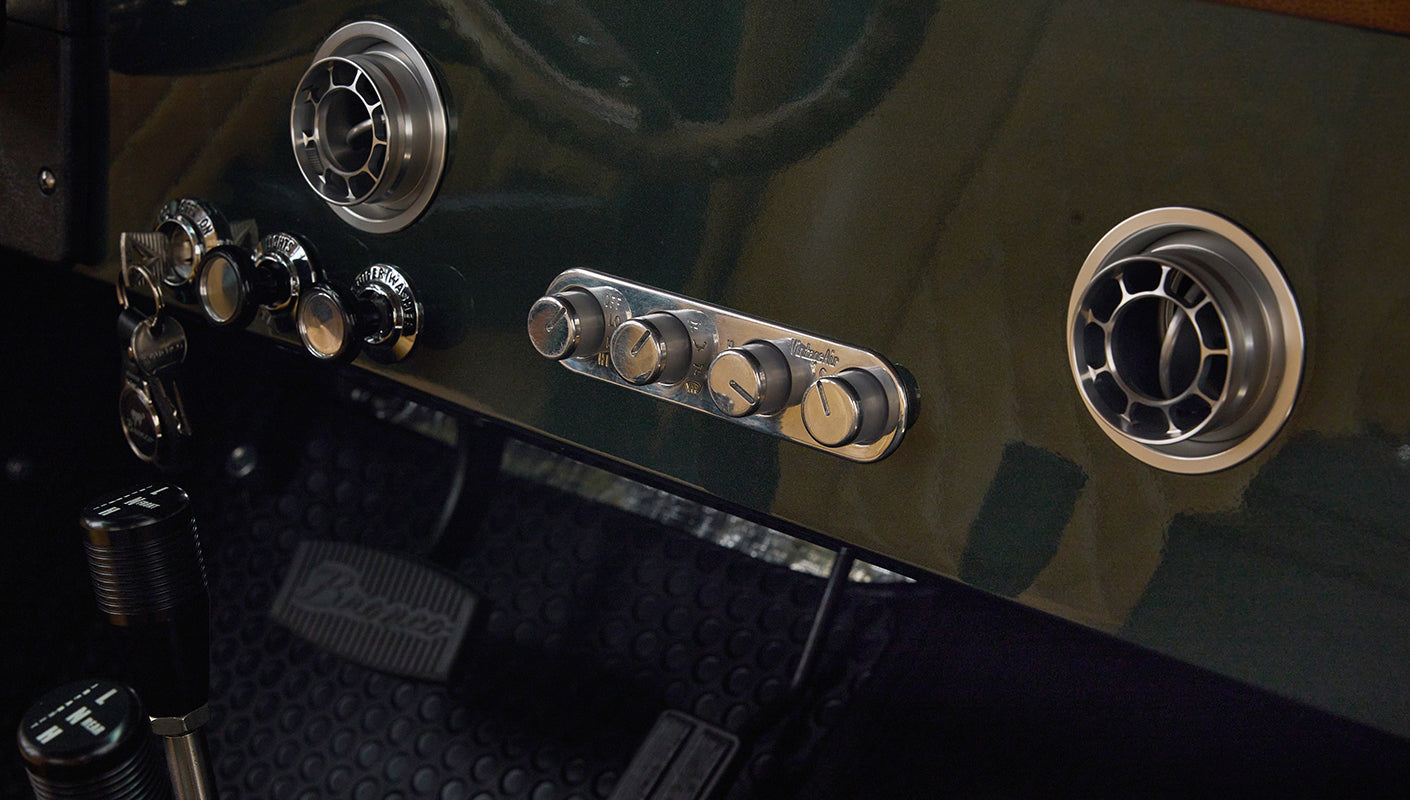 Close-up of gear shifters and surrounding black rubber floor mat inside Classic Ford Bronco interior