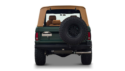 Rear view of Classic Ford Bronco in dark forest green with tan soft top and mounted spare tire