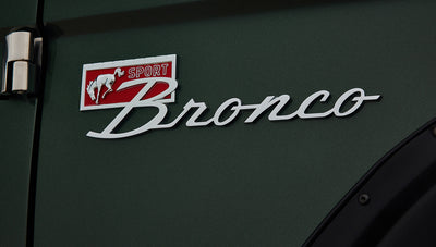 Close-up of Classic Ford Bronco side emblem reading Sport Bronco on dark green body.