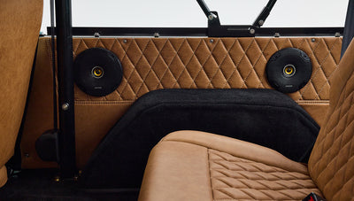 Close-up of tan quilted door panel with two black round speakers inside Classic Ford Bronco.