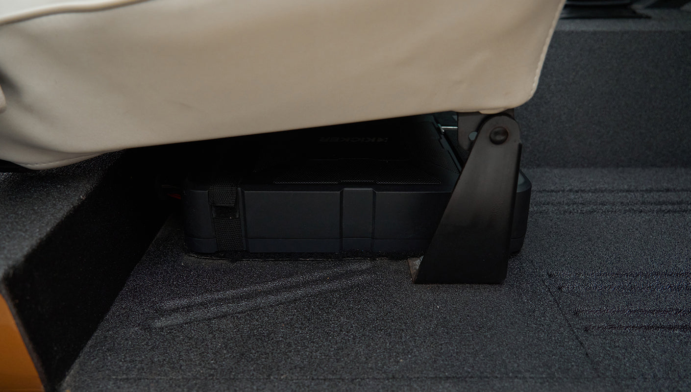 Black electronic device mounted under a white seat inside Classic Ford Bronco