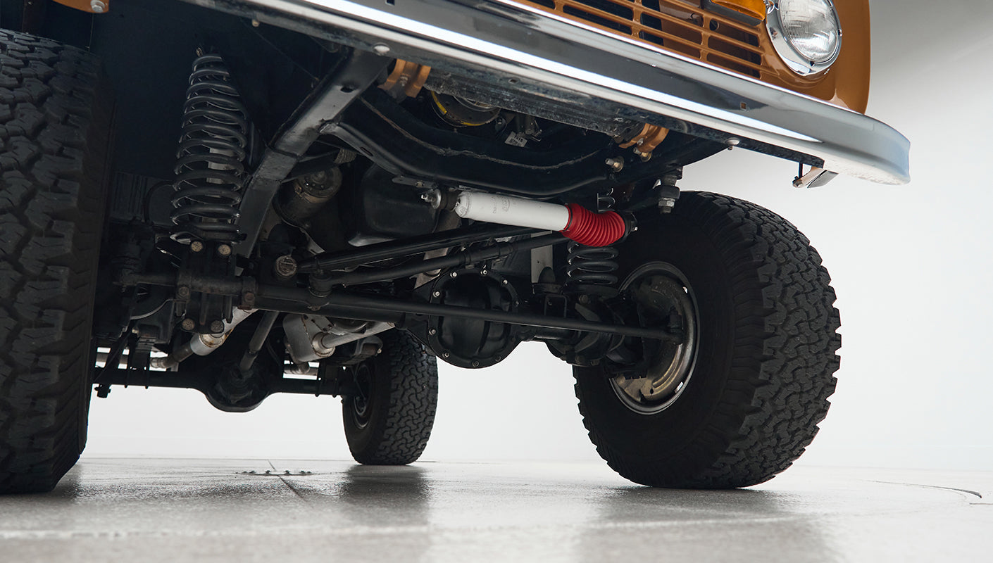 Underneath view of front suspension, axle, and tires of Classic Ford Bronco