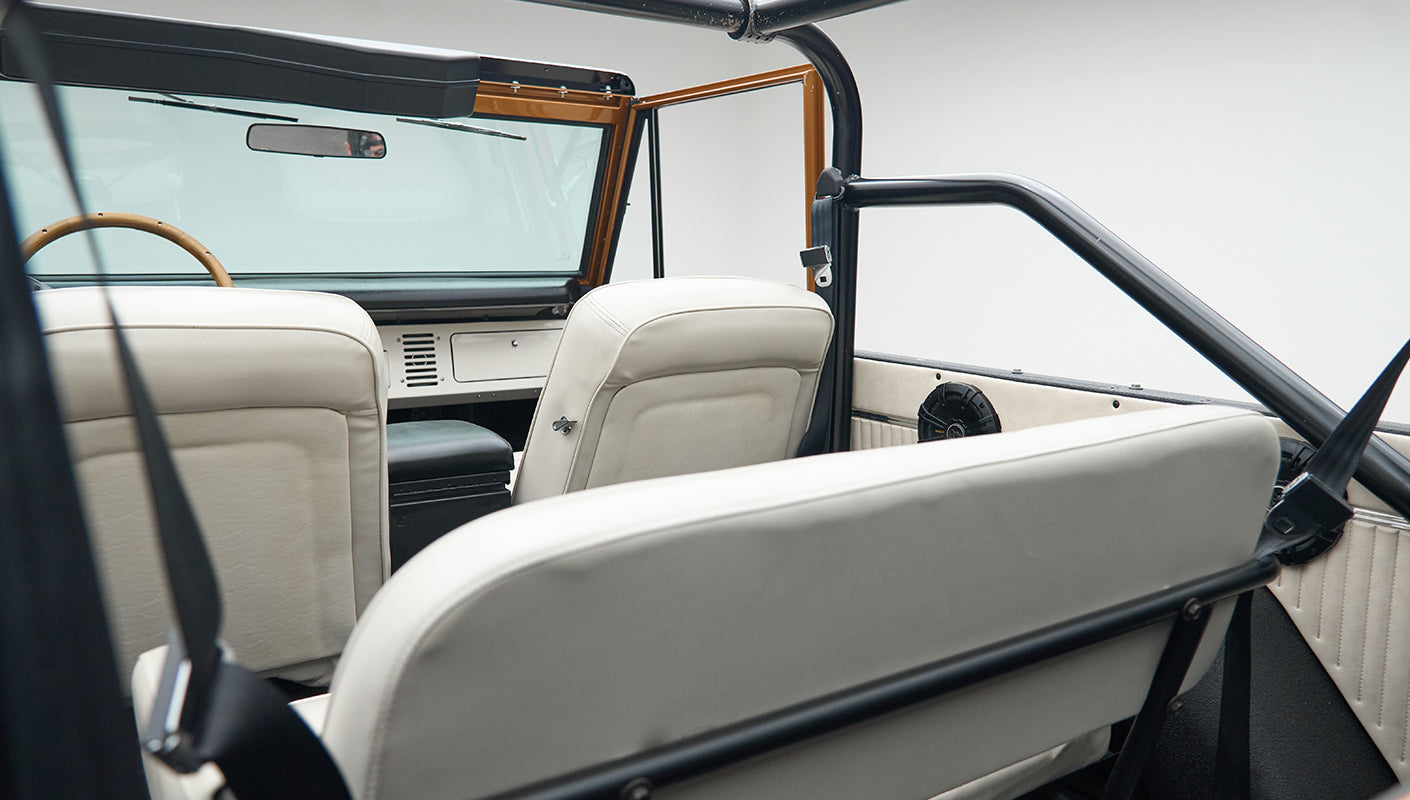 Interior rear view of Classic Ford Bronco showing white seats and roll cage