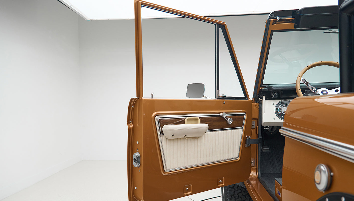 Classic Ford Bronco driver side door open showing interior door panel and side mirror
