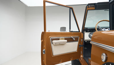 Classic Ford Bronco driver side door open showing interior door panel and side mirror