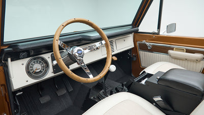 Classic Ford Bronco dashboard with wooden steering wheel, speedometer, and gear shifter