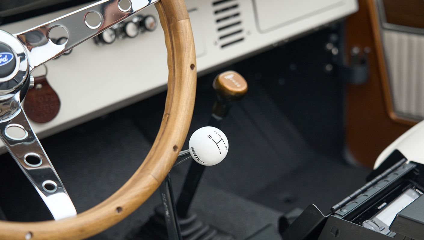 Close-up of Classic Ford Bronco wooden steering wheel and white Hurst gear shift knob