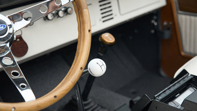 Close-up of Classic Ford Bronco wooden steering wheel and white Hurst gear shift knob