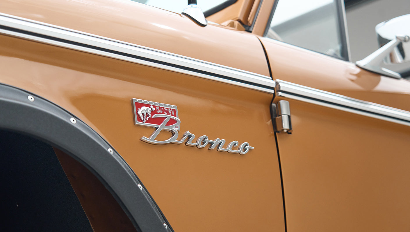 Close-up of Classic Ford Bronco badge and side mirror on a Saddle Bronze vehicle