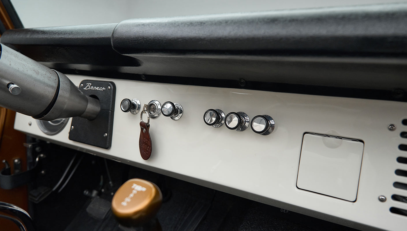 Classic Ford Bronco dashboard with knobs, ignition with key, and gear shifters