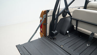 Open rear cargo area of Classic Ford Bronco showing black bed liner and rear seat