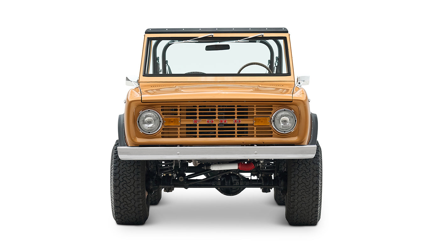 Front view of saddle bronze Classic Ford Bronco with round headlights and black wheel arches on white background