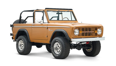 Side view of classic Ford Bronco in saddle bronze color with black wheel arches and white interior on white background