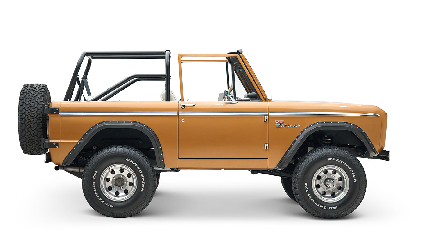 Side profile of Classic Ford Bronco in saddle bronze with black wheel arches and open roof on white background