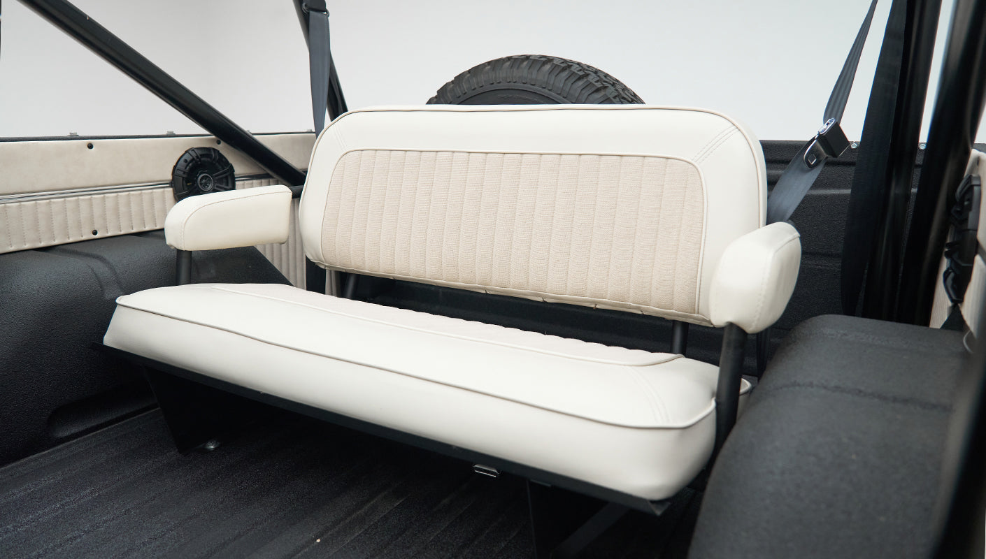 Rear seat view of Classic Ford Bronco showing white bench seat and black roll bar
