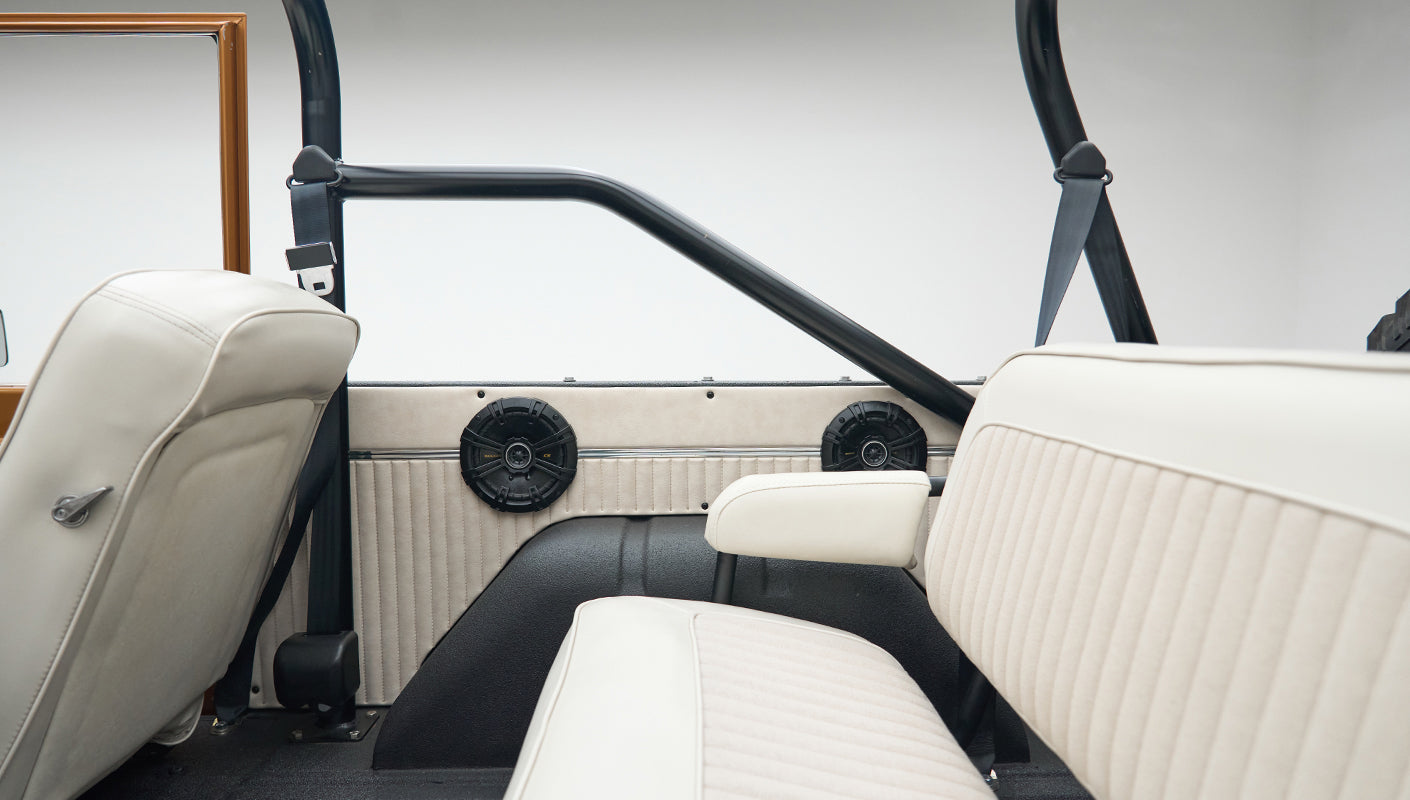Close-up of rear seat area with black speakers and white upholstery inside Classic Ford Bronco