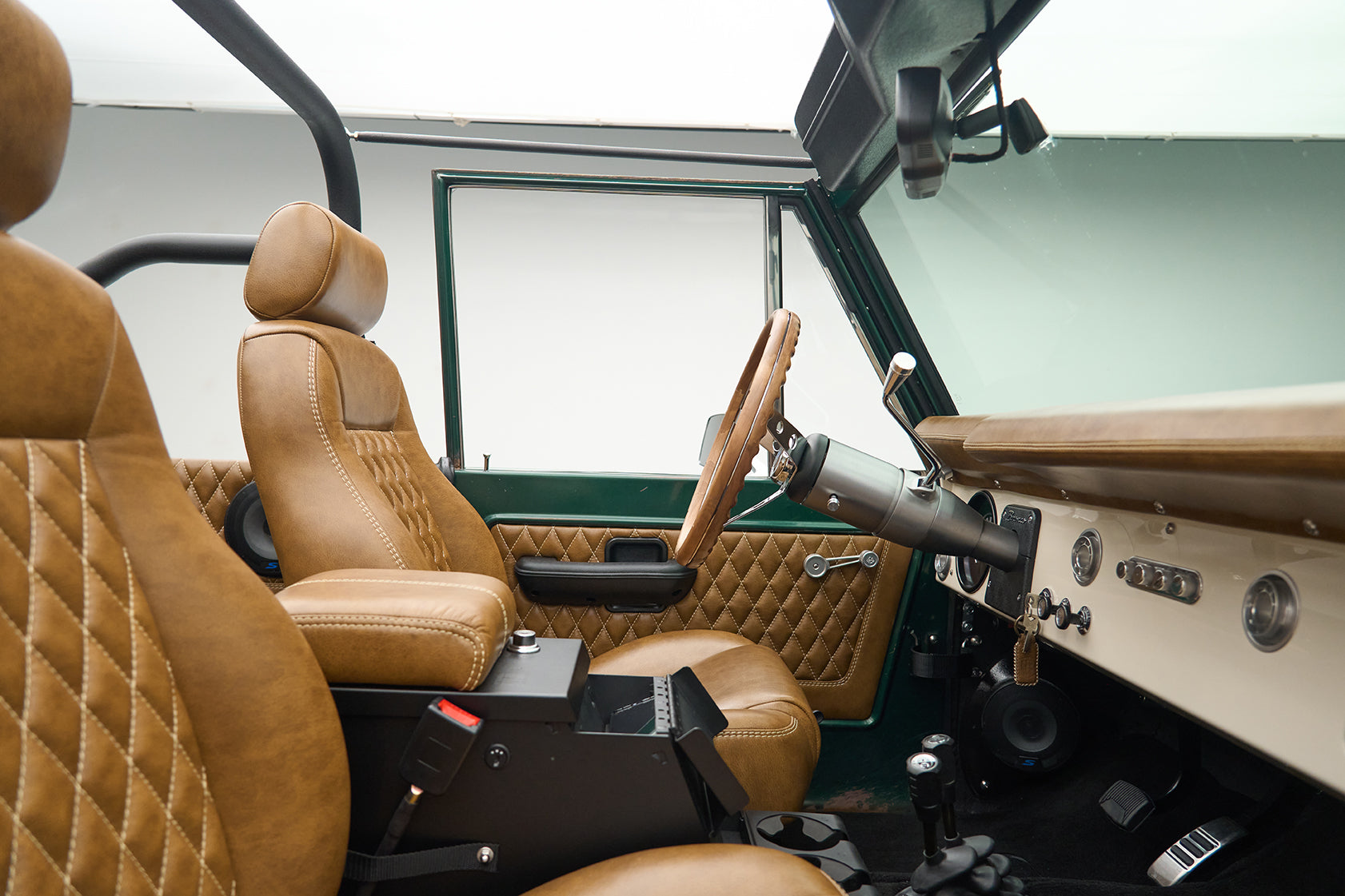 Classic Ford Bronco interior with tan leather quilted seats and green door panel