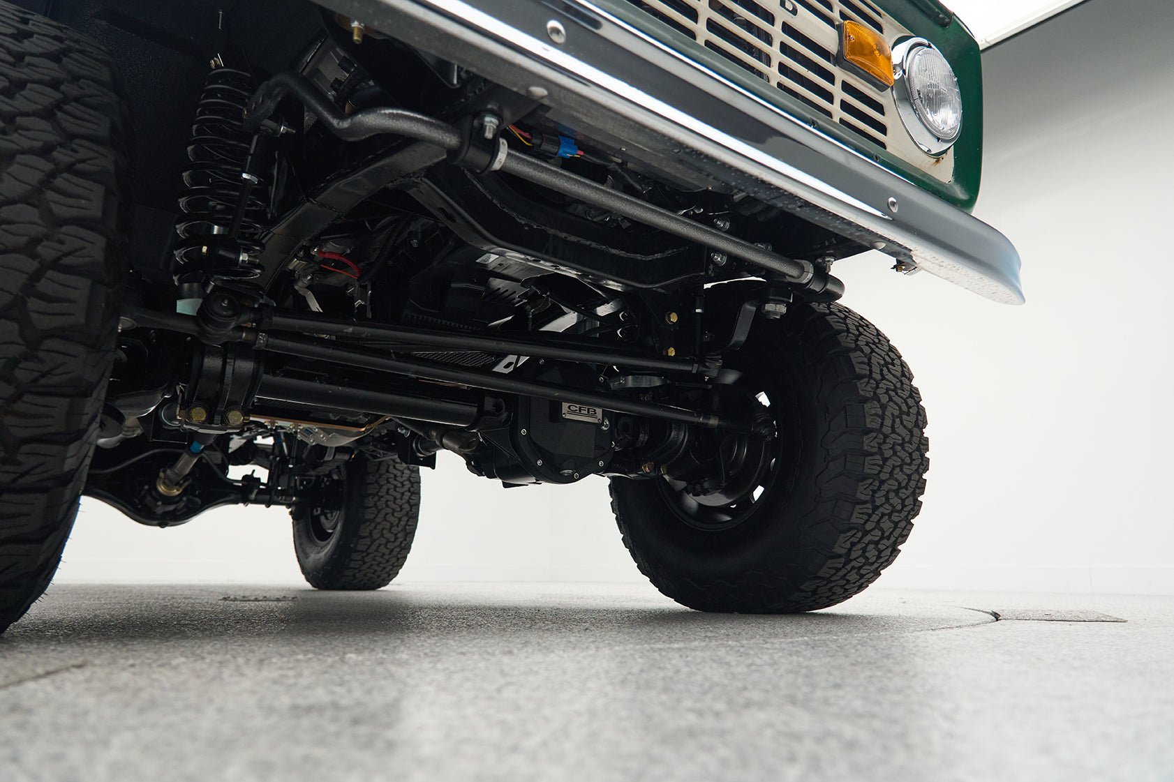 Underside view of a Classic Ford Bronco showing suspension components and front tires.