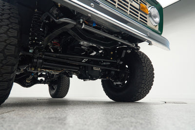 Underside view of a Classic Ford Bronco showing suspension components and front tires.