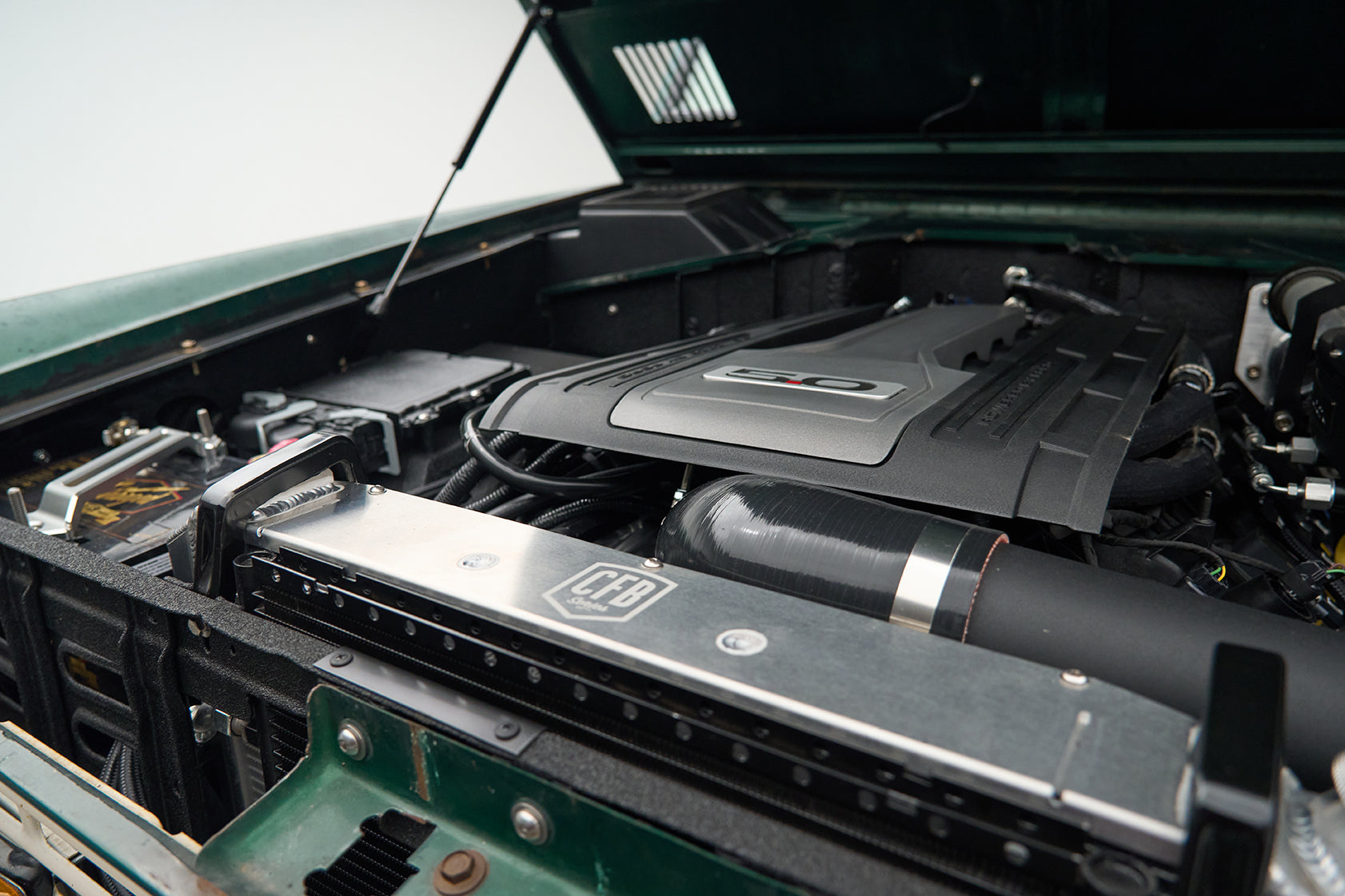 Engine bay of a Classic Ford Bronco with a 5.0-liter engine and CFB branded metal radiator support.