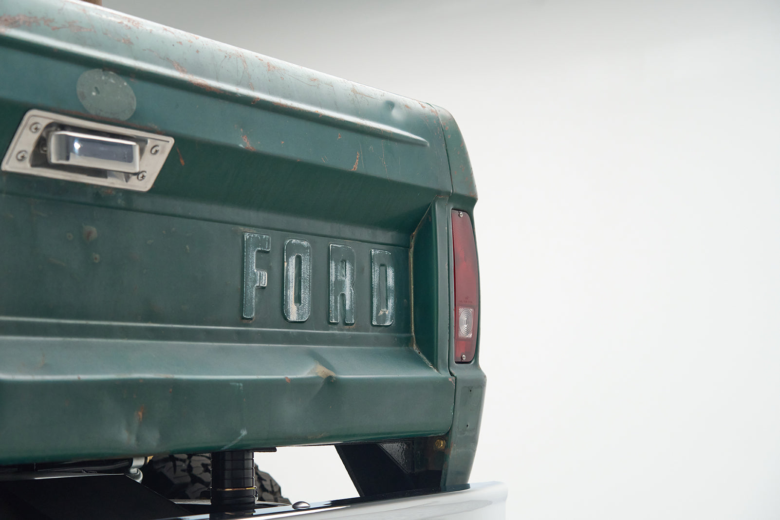 Rear section of green Ford Bronco with FORD embossed and visible taillight