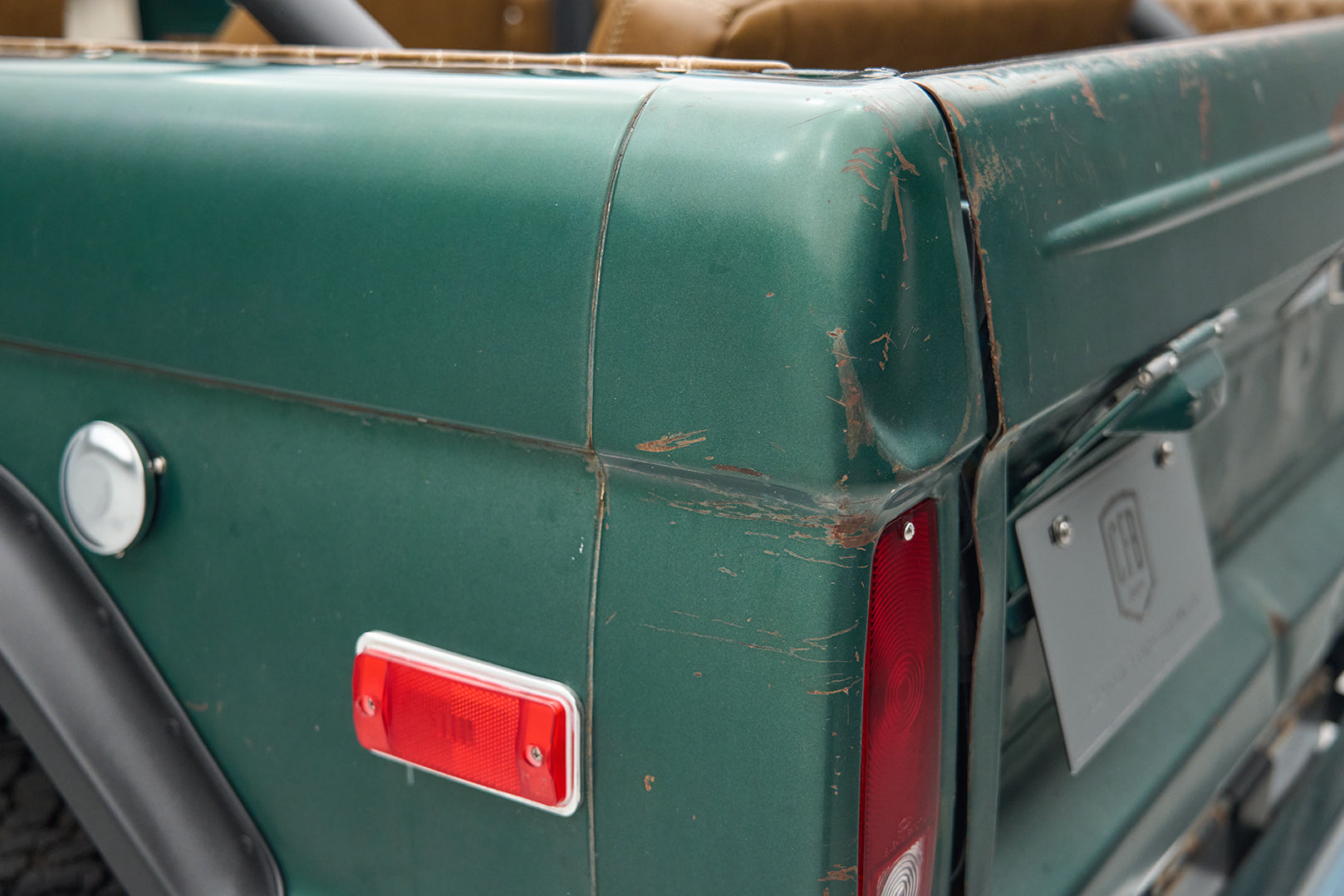 Close view of rear corner of green Ford Bronco showing taillight and scratches