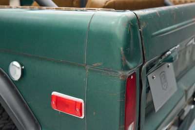 Close view of rear corner of green Ford Bronco showing taillight and scratches