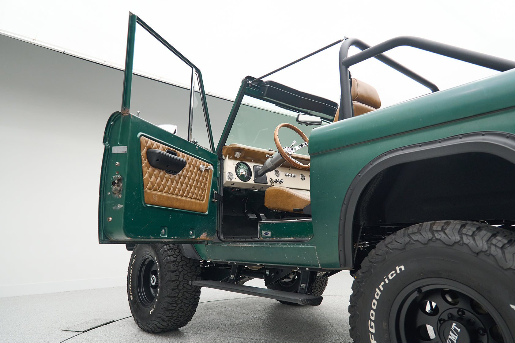 Open driver's door revealing steering wheel and dashboard inside Ford Bronco
