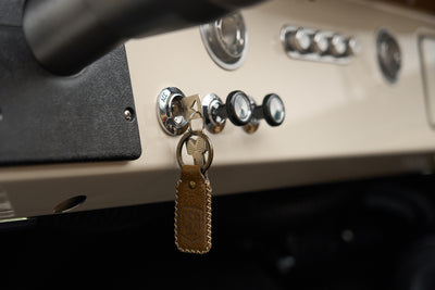 Close-up of speedometer and ignition key with leather key fob hanging from Classic Ford Bronco dashboard.