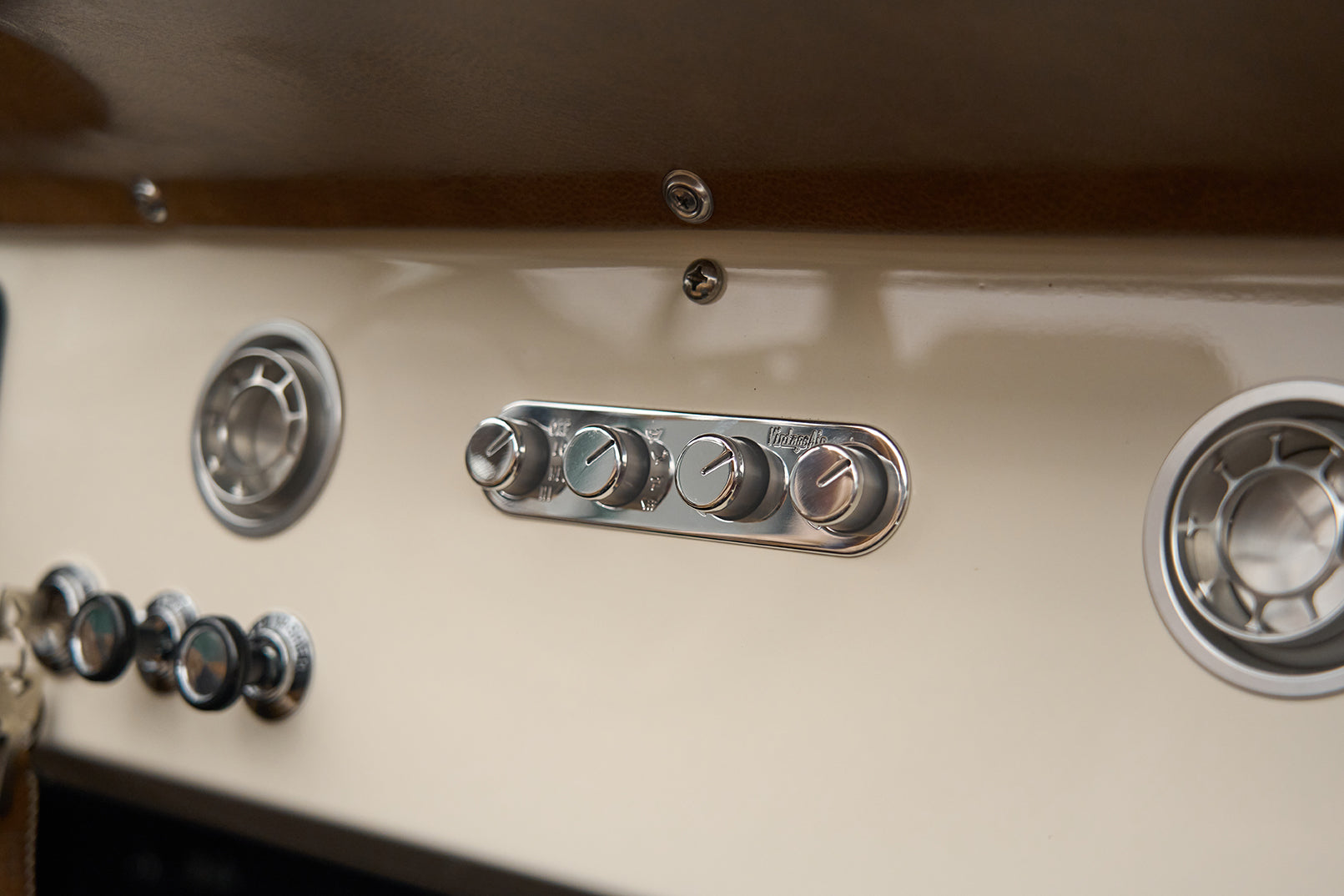 Close-up of ignition switch and chrome control knobs on cream dashboard of Classic Ford Bronco.