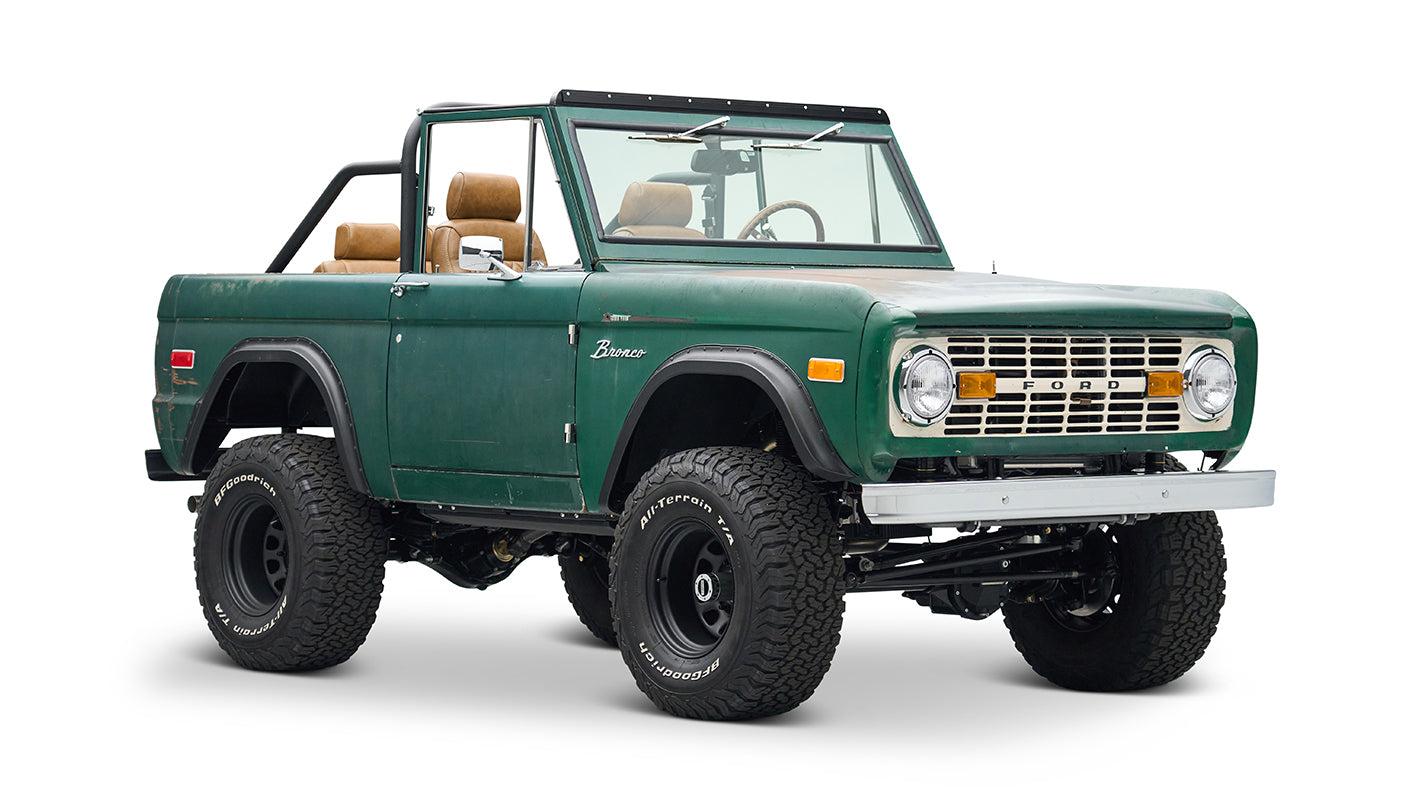 Rear side view of dark green Classic Ford Bronco with spare tire mounted on back