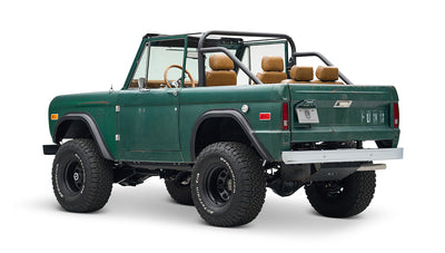 Classic Ford Bronco in green with tan seats and roll bars, rear side angle on white background