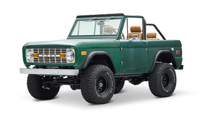 Classic Ford Bronco in green with tan interior, front side view on white background