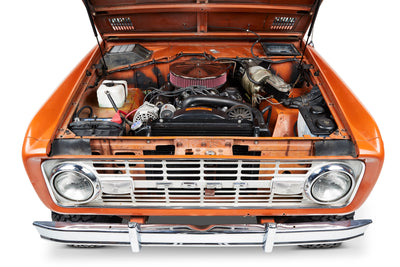 Classic Ford Bronco front with open hood showing engine and orange body.