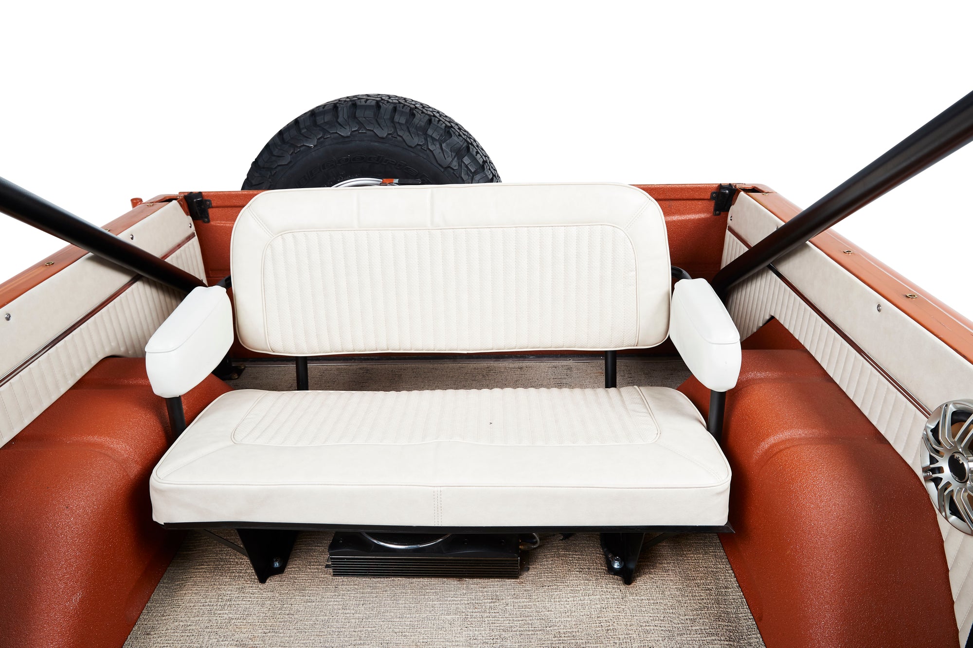 Rear seat and interior of a Classic Ford Bronco with white upholstery and a spare tire mounted behind.