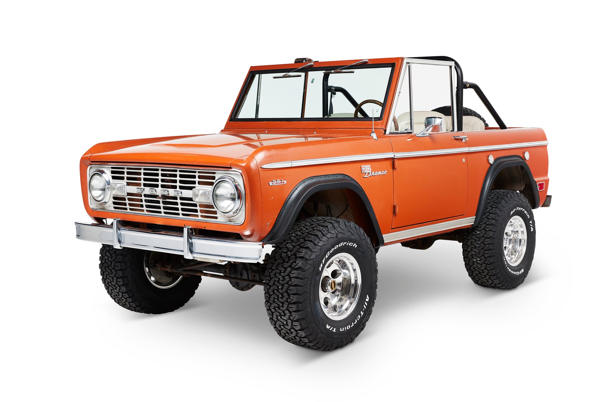 Three-quarter front view of orange Classic Ford Bronco with large tires and open top.