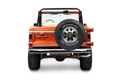 Rear view of orange Classic Ford Bronco with spare tire mounted on tailgate.