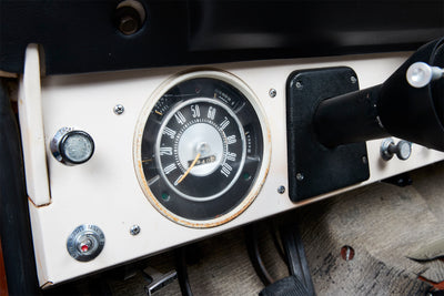 Close-up of a classic Ford Bronco dashboard with speedometer, choke knob, and fuel tank selector switch.