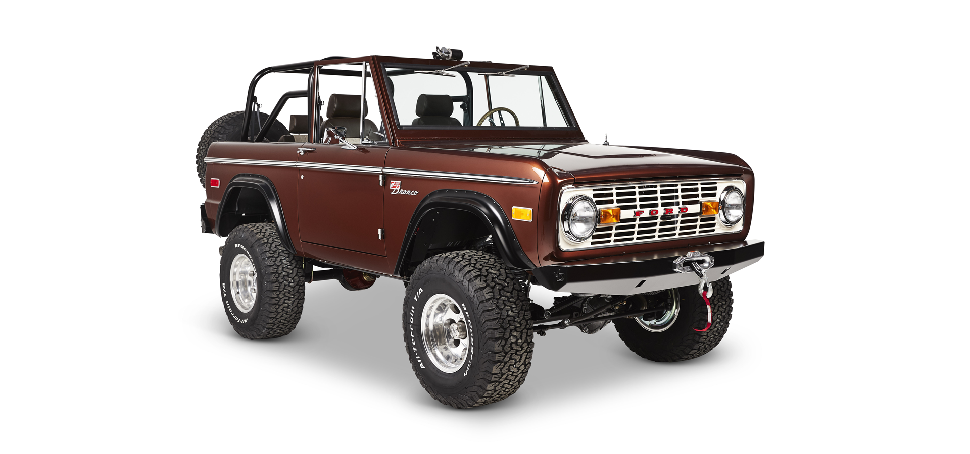 Brown Classic Ford Bronco side view showing off-road tires, chrome wheel rims, and open cabin with seats