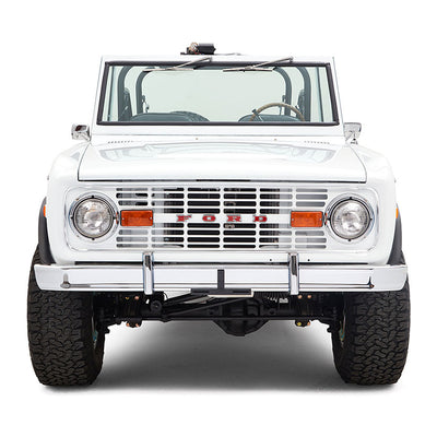 Front view of white Classic Ford Bronco with orange reflector lights and chrome bumper against white background