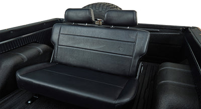 Black rear seat interior of Classic Ford Bronco with headrests and textured truck bed walls.