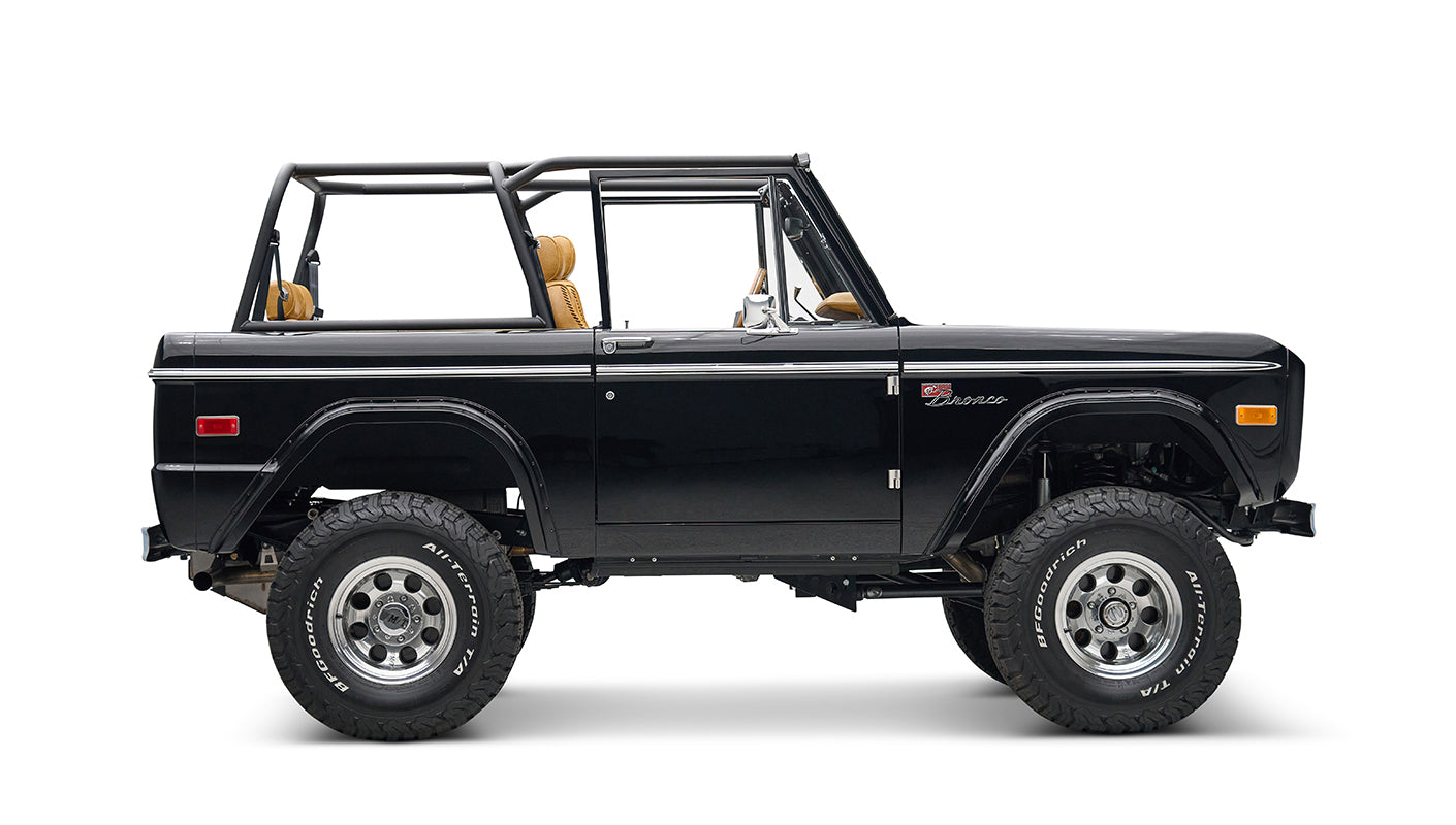 Side view of black Classic Ford Bronco with tan seats, lifted suspension, and chrome wheels