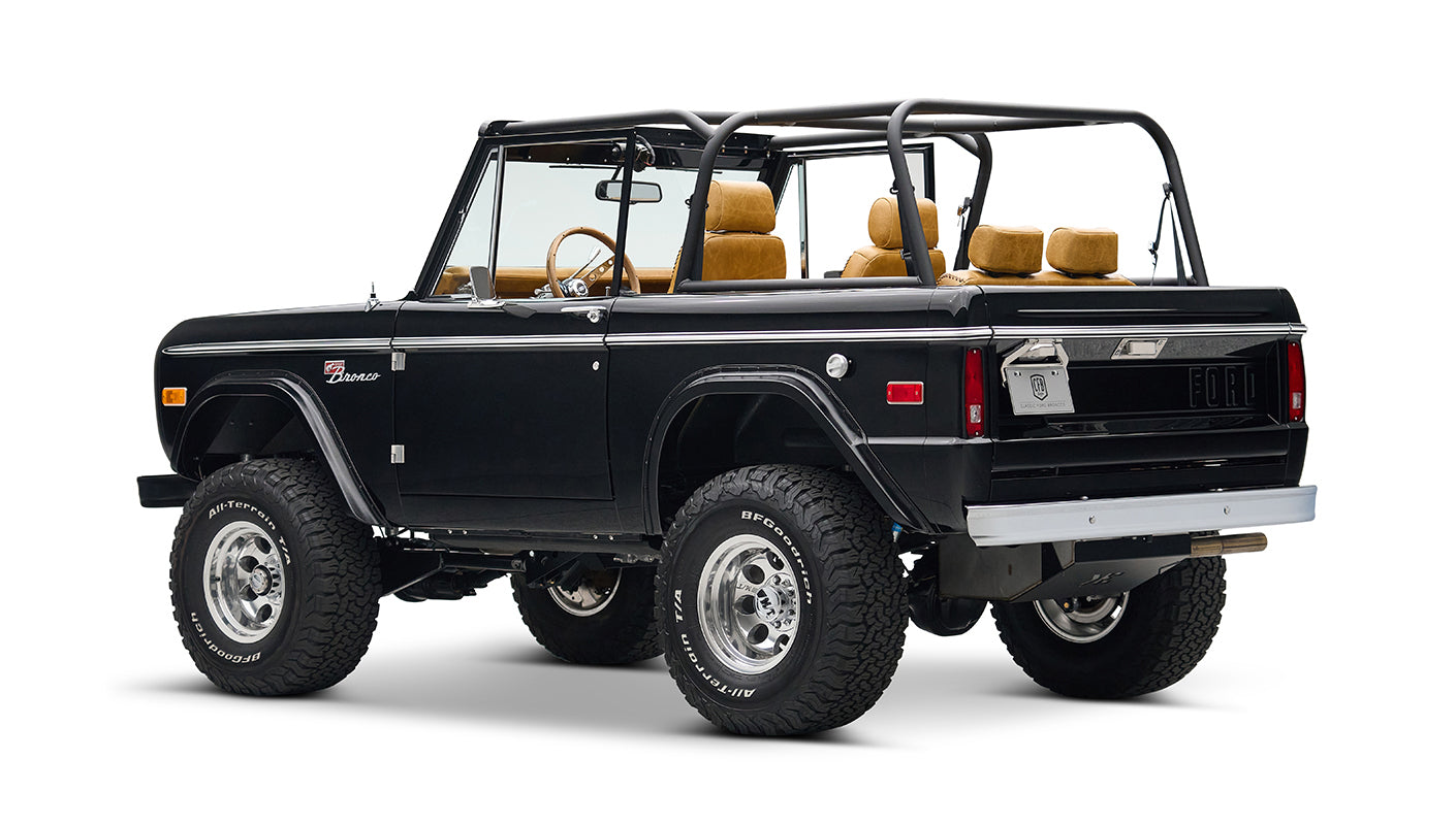 Rear side view of black Classic Ford Bronco with tan seats, chrome wheels, and lifted suspension