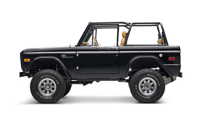 Side view of black Classic Ford Bronco with tan seats, lifted suspension, and chrome wheels