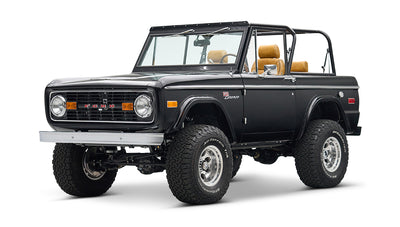 Black Classic Ford Bronco with tan seats, lifted suspension, and chrome wheels angled front right