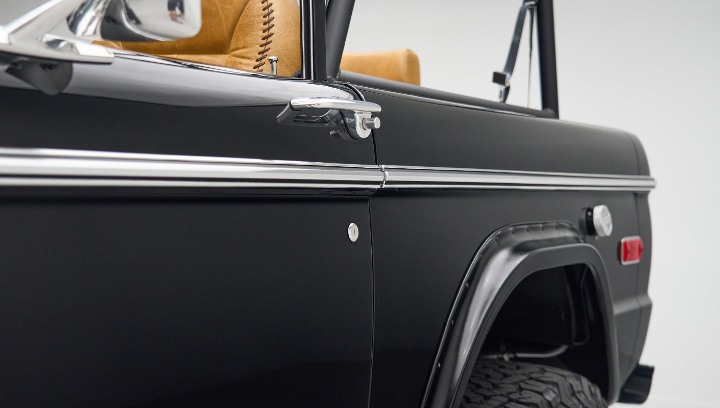 Side view of black Classic Ford Bronco door with tan leather interior and steering wheel